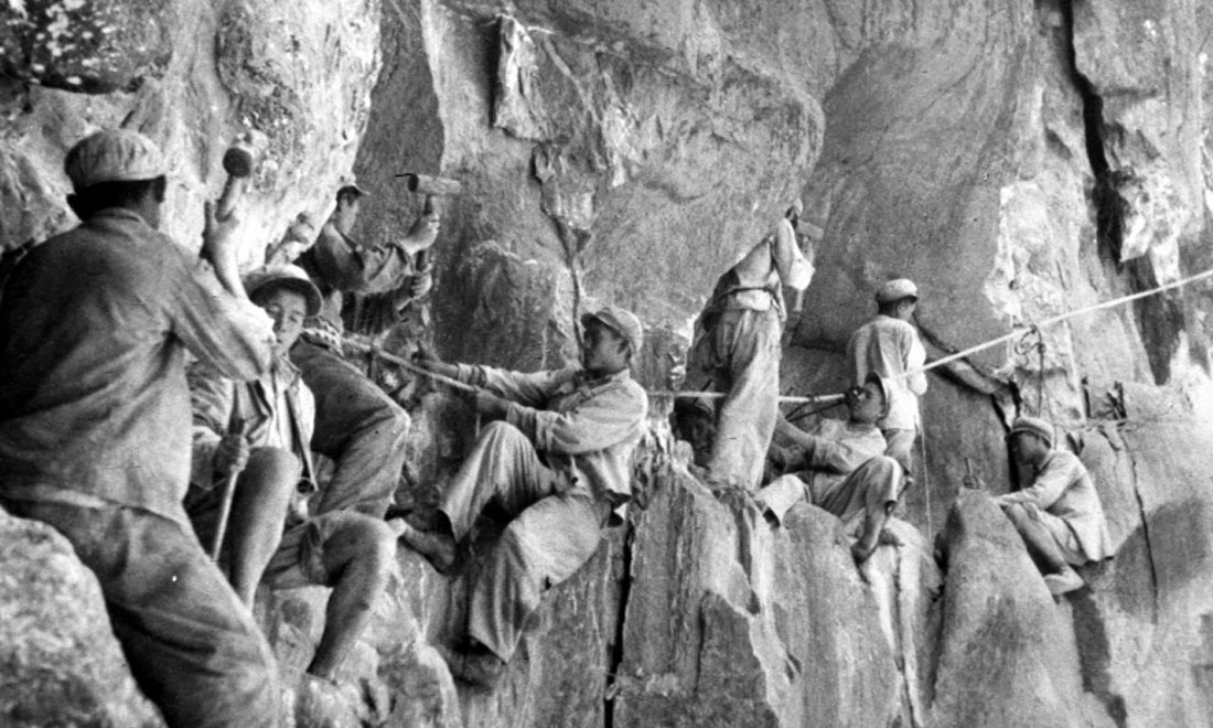 1954年，修筑康藏公路的解放軍戰(zhàn)士們?cè)谂瓋砂兜膽已露副谏媳偕街?。新華社稿 李萬(wàn)春、張加里攝